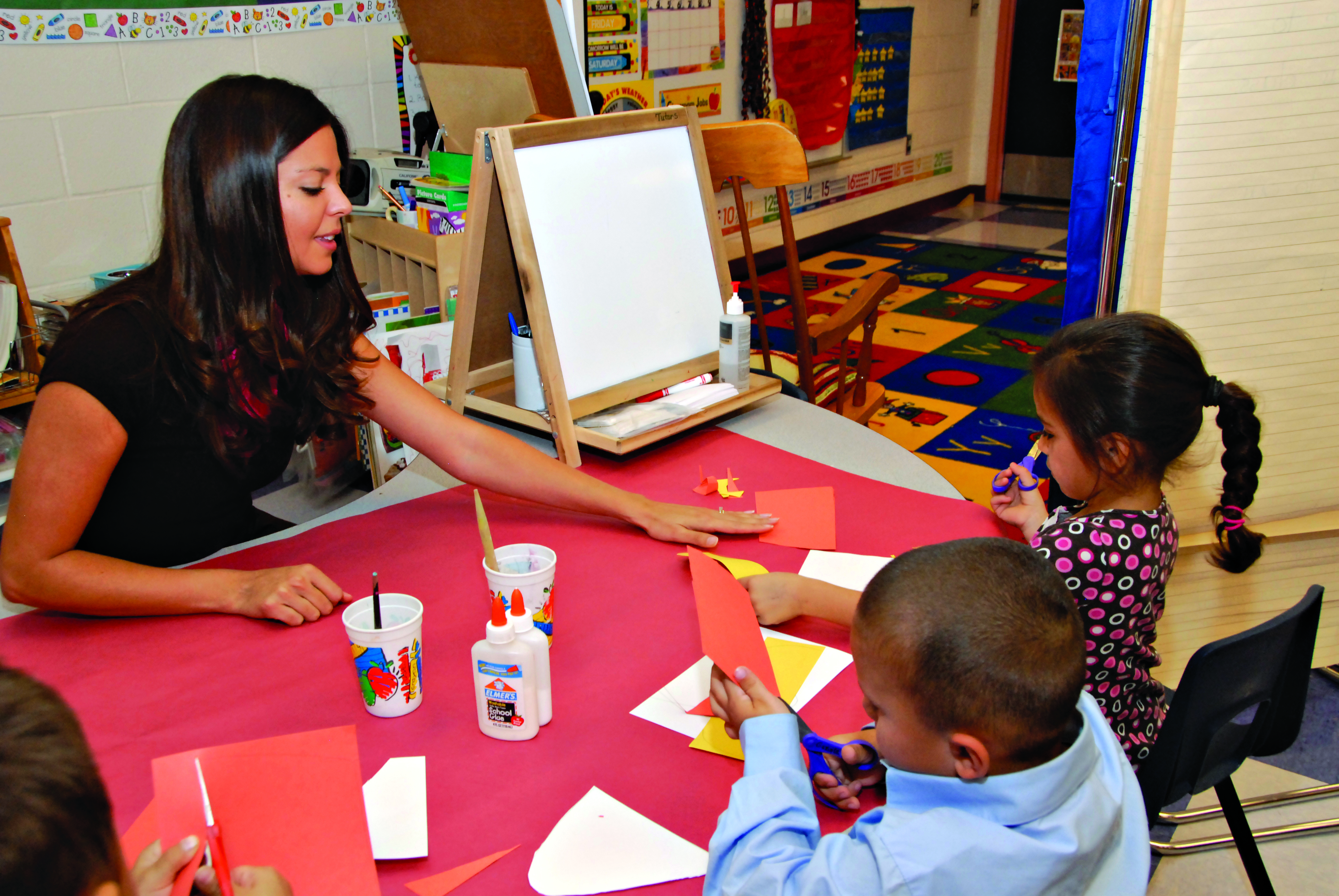 A teacher helps her students with a craft project